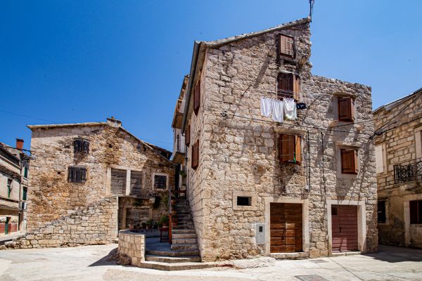 stone shuttered houses against a blue sky in Vis
